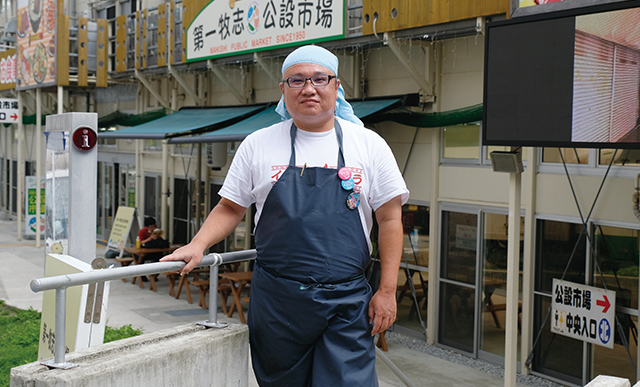 仮設の第一牧志公設市場の前に立つ粟国氏